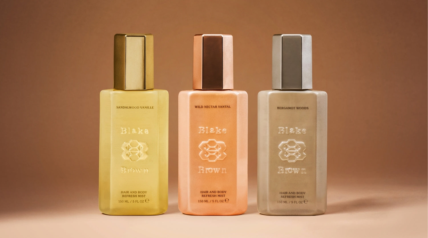 Blake Brown Hair and Body Refresh Mists in three signature scents—Sandalwood Vanille, Wild Nectar Santal, and Bergamot Woods—displayed side by side on a warm neutral background.